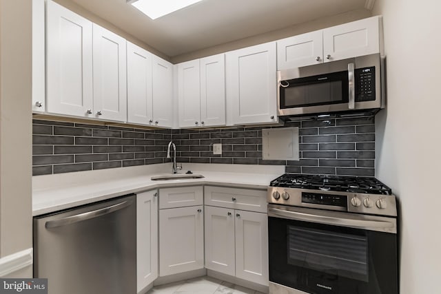 kitchen with tasteful backsplash, appliances with stainless steel finishes, sink, and white cabinetry