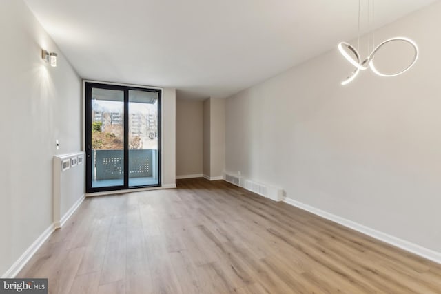 empty room featuring floor to ceiling windows and light wood-type flooring