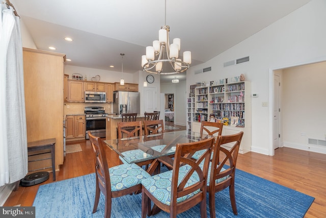 dining room featuring lofted ceiling, a chandelier, and light hardwood / wood-style floors