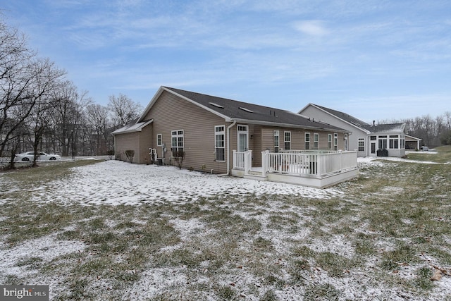 snow covered back of property with a wooden deck