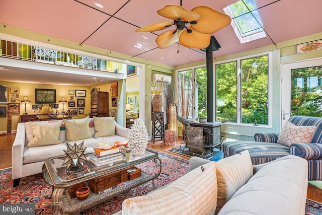 interior space with ceiling fan, a skylight, and a wood stove