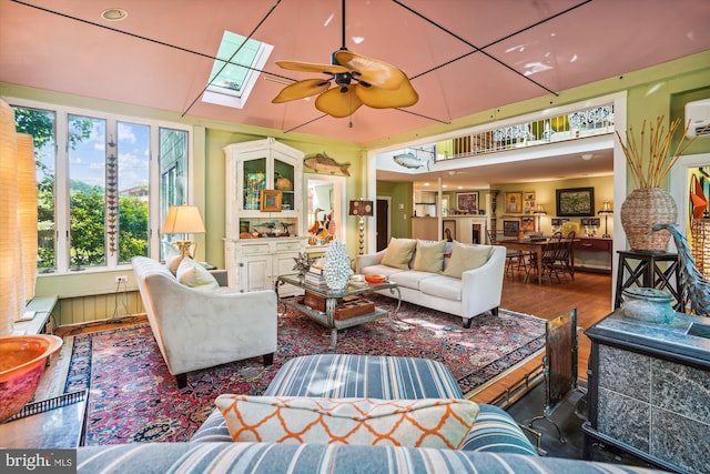 living room with ceiling fan, hardwood / wood-style floors, and a skylight