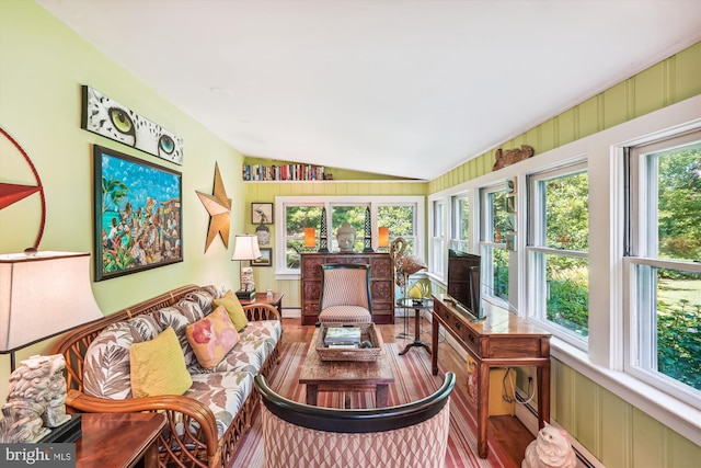 sunroom / solarium featuring vaulted ceiling, plenty of natural light, and a baseboard heating unit