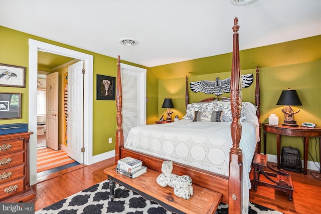 bedroom featuring ensuite bath, vaulted ceiling, and light hardwood / wood-style floors