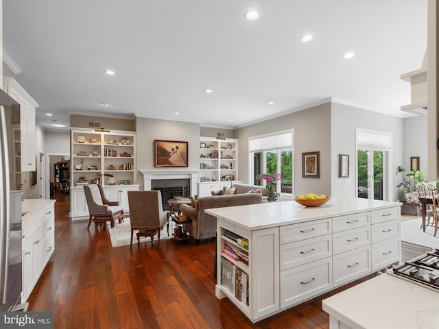 kitchen with dark wood-type flooring, white cabinetry, ornamental molding, and a kitchen island