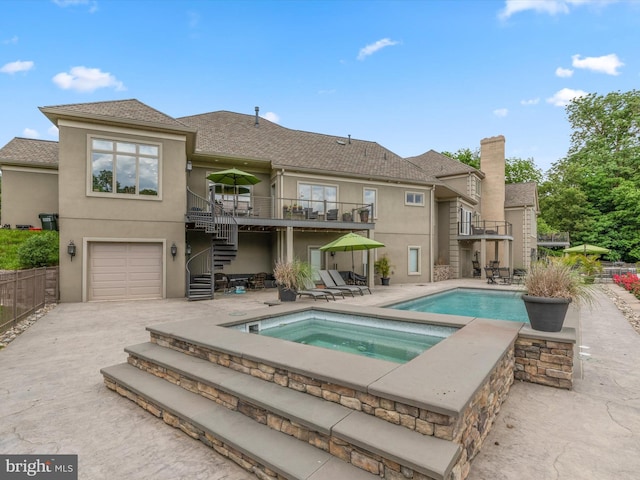 rear view of house with a patio area, a swimming pool with hot tub, a garage, and a balcony