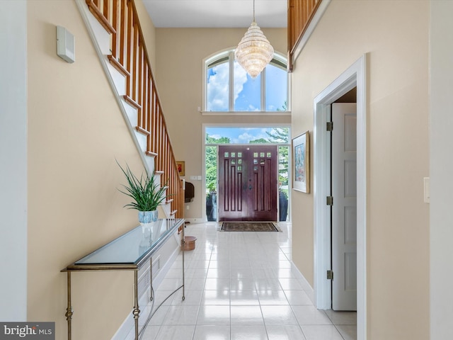 entryway featuring a towering ceiling, light tile patterned flooring, and an inviting chandelier