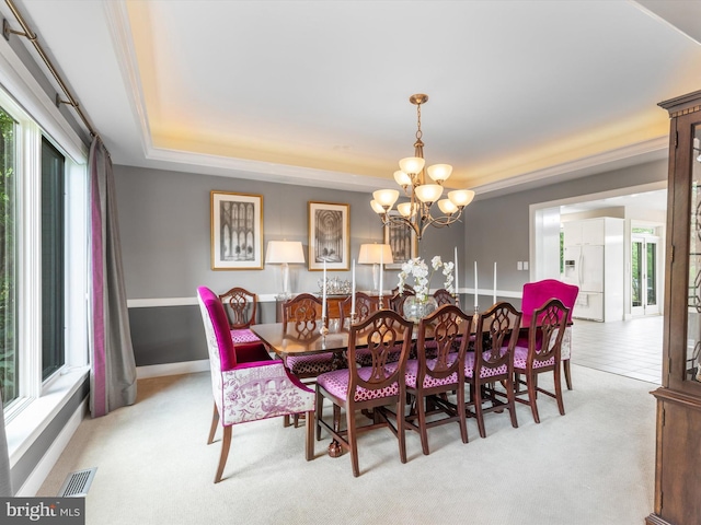 dining room with a wealth of natural light, a tray ceiling, and a chandelier