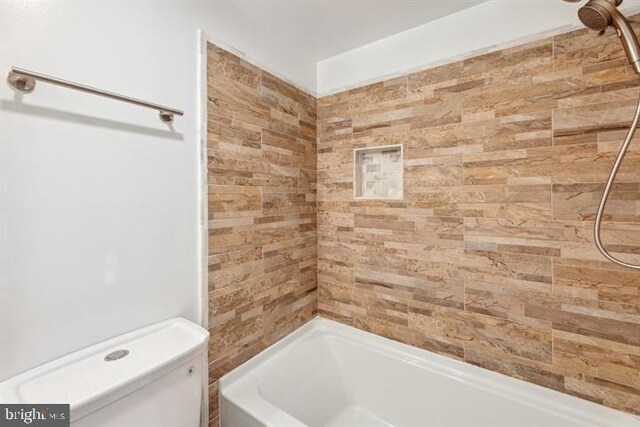 bathroom featuring toilet and tiled shower / bath