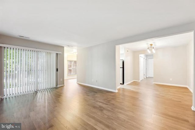 unfurnished room with an inviting chandelier and hardwood / wood-style flooring