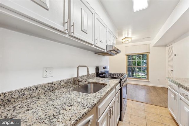 kitchen featuring white cabinets, sink, light stone counters, light tile patterned floors, and stainless steel range with gas stovetop