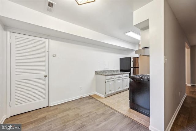 kitchen with light hardwood / wood-style floors, white cabinets, and stainless steel refrigerator