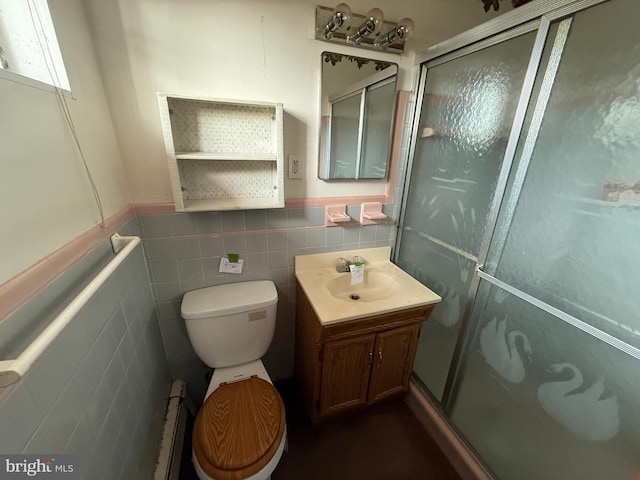 bathroom with toilet, a shower with shower door, a baseboard radiator, tile walls, and vanity