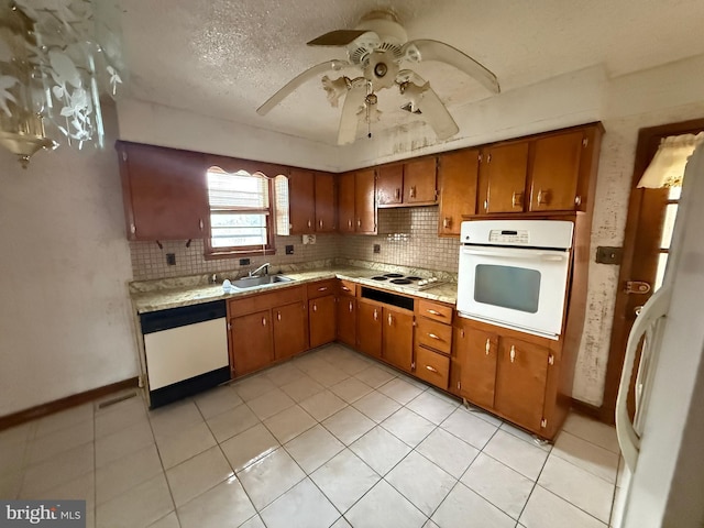 kitchen featuring white appliances, a textured ceiling, sink, ceiling fan, and light tile patterned floors