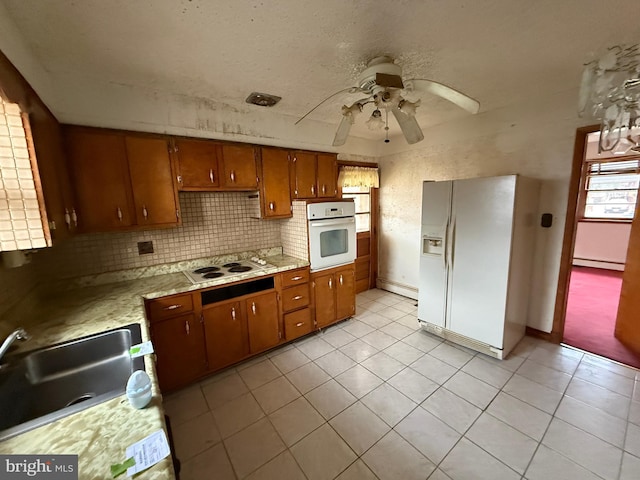 kitchen featuring a baseboard heating unit, ceiling fan, decorative backsplash, white appliances, and sink