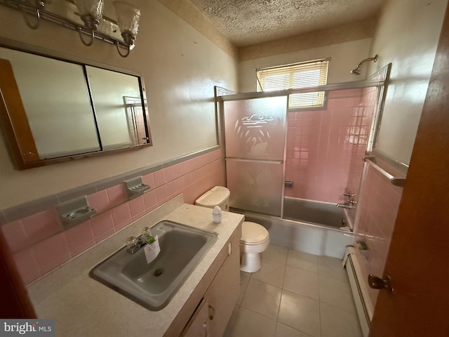 full bathroom with toilet, bath / shower combo with glass door, baseboard heating, tile walls, and a textured ceiling