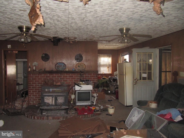 living room with a wood stove and wooden walls