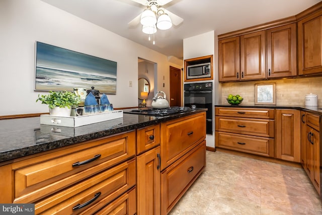 kitchen featuring backsplash, ceiling fan, dark stone countertops, and black appliances