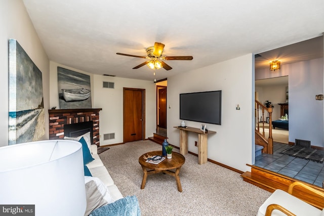 carpeted living room with a brick fireplace and ceiling fan