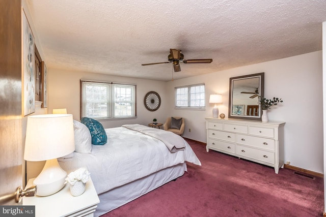 bedroom featuring ceiling fan, a textured ceiling, and dark colored carpet