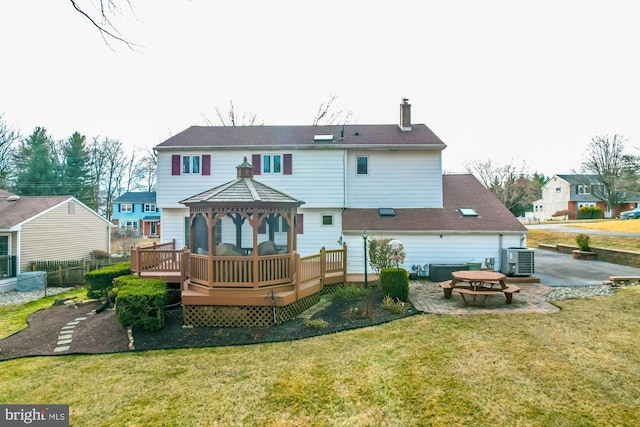 rear view of property with a deck, a yard, a gazebo, central AC, and a patio