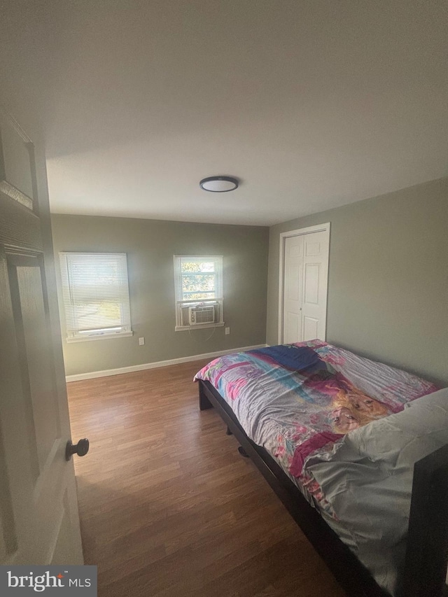 bedroom with hardwood / wood-style floors, a closet, and cooling unit