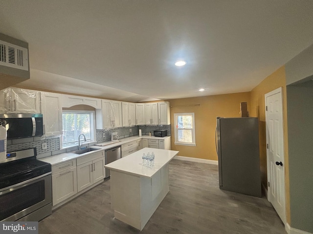 kitchen featuring a kitchen island, white cabinetry, stainless steel appliances, decorative backsplash, and sink