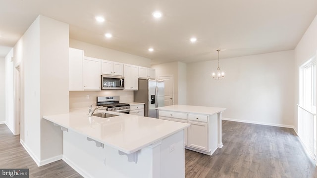 kitchen with kitchen peninsula, stainless steel appliances, dark hardwood / wood-style flooring, pendant lighting, and white cabinets