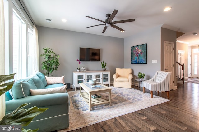 living room featuring dark wood-type flooring and ceiling fan