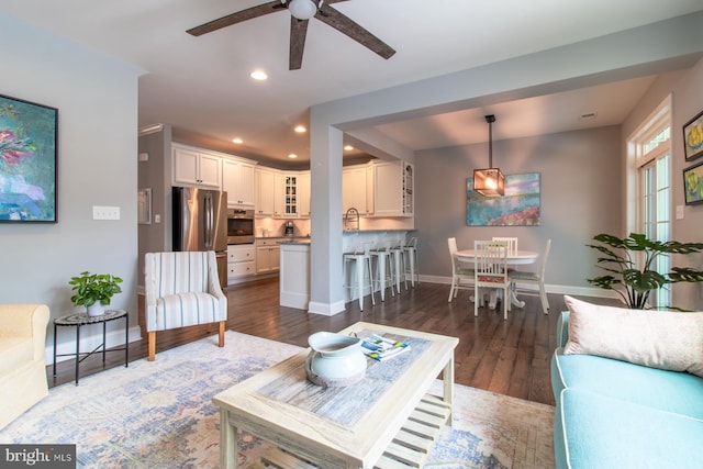 living room with ceiling fan and dark hardwood / wood-style flooring