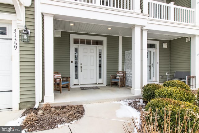 view of exterior entry featuring a balcony and a porch