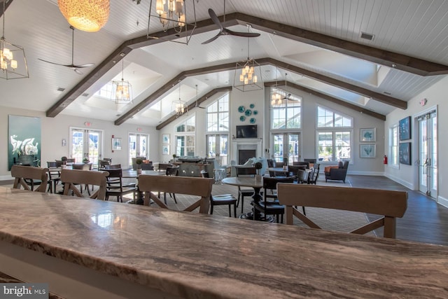 dining space featuring hardwood / wood-style floors, ceiling fan with notable chandelier, high vaulted ceiling, beam ceiling, and french doors