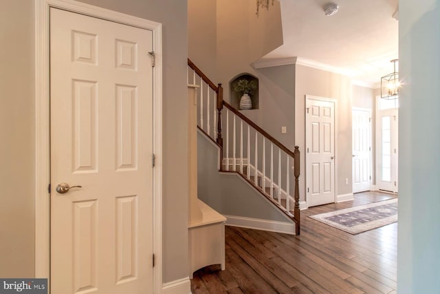 foyer entrance featuring crown molding, dark hardwood / wood-style floors, and an inviting chandelier