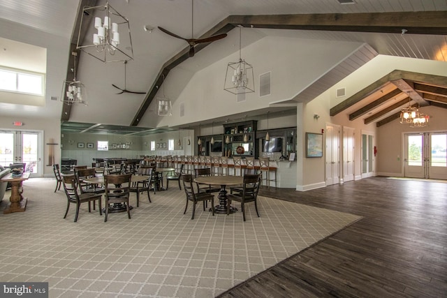 dining space with french doors, an inviting chandelier, high vaulted ceiling, and wood-type flooring