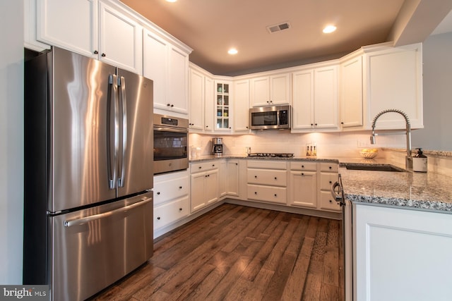 kitchen featuring sink, appliances with stainless steel finishes, white cabinetry, light stone countertops, and dark hardwood / wood-style flooring