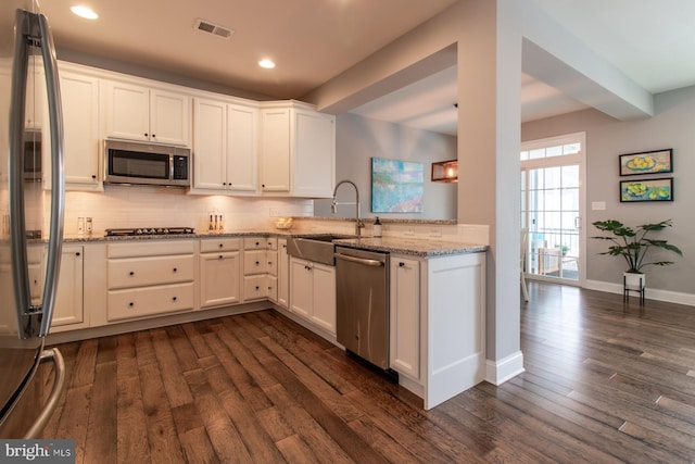 kitchen featuring white cabinetry, appliances with stainless steel finishes, dark hardwood / wood-style floors, and light stone counters