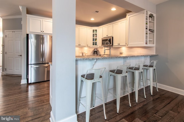 kitchen with tasteful backsplash, dark wood-type flooring, white cabinets, and appliances with stainless steel finishes