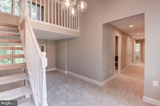 stairs featuring plenty of natural light, carpet flooring, and a high ceiling