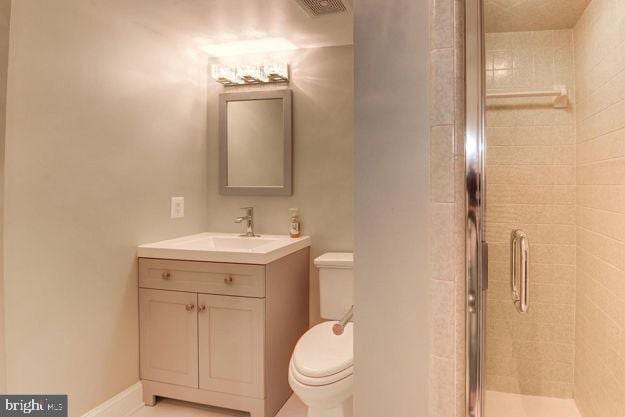 bathroom featuring a shower with door, toilet, and vanity