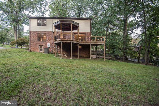 rear view of house featuring a lawn and a wooden deck