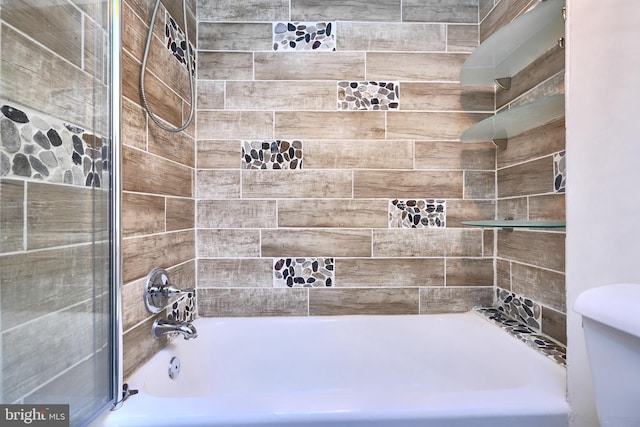 bathroom featuring toilet and tiled shower / bath