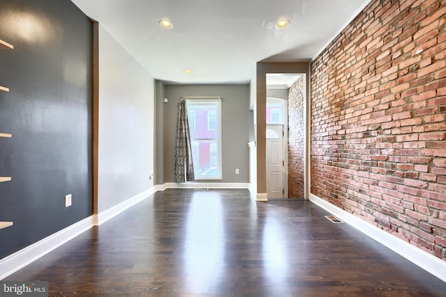 empty room with brick wall and dark hardwood / wood-style floors