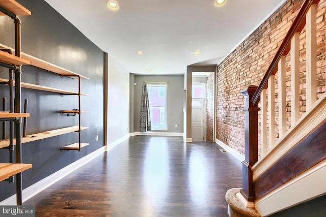 entryway with brick wall and dark hardwood / wood-style flooring