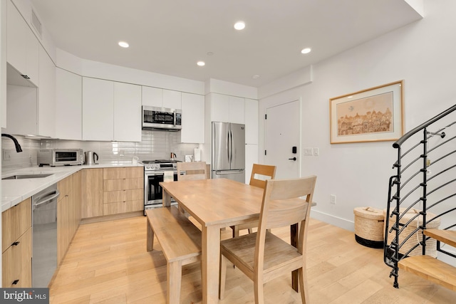 kitchen with stainless steel appliances, light hardwood / wood-style flooring, white cabinetry, and sink