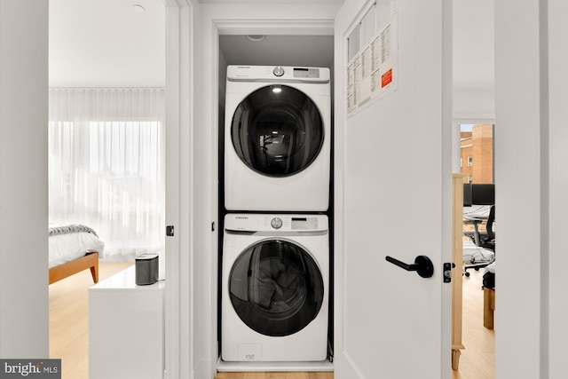 clothes washing area with stacked washer / drying machine and light hardwood / wood-style floors