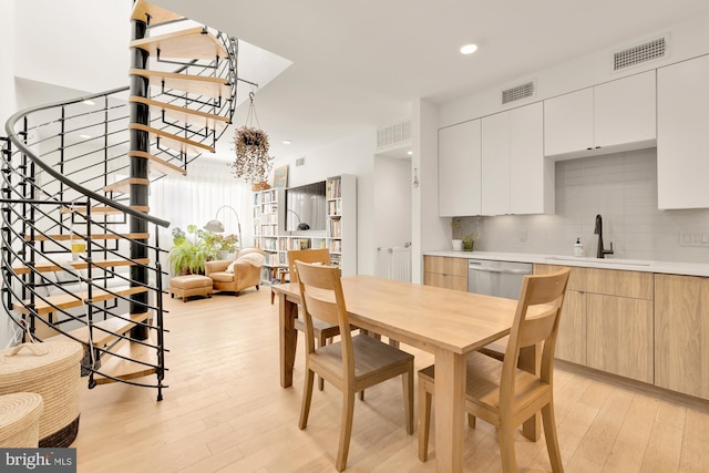 dining area with sink, a chandelier, and light hardwood / wood-style floors