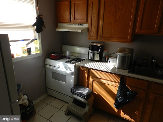 kitchen with light tile patterned flooring, stainless steel fridge, sink, and white gas range oven