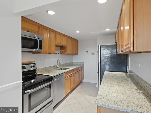 kitchen featuring light stone counters, appliances with stainless steel finishes, sink, and light tile patterned floors