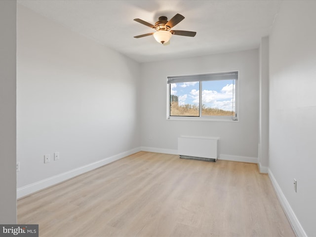 unfurnished room featuring radiator heating unit, ceiling fan, and light wood-type flooring