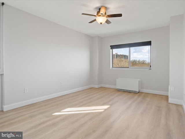 unfurnished room featuring radiator, ceiling fan, and light hardwood / wood-style flooring